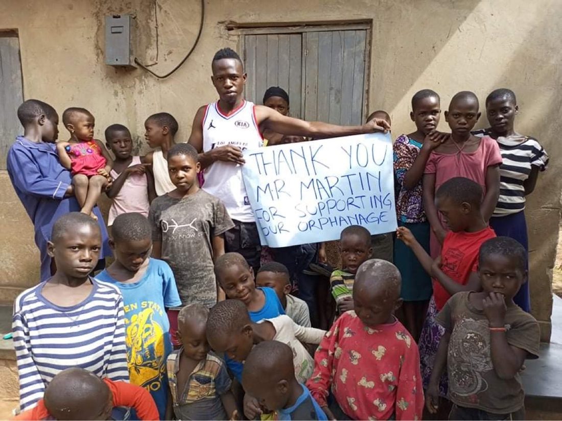A caregiver and a large group of children at Orient Children's Home holding a thank-you sign